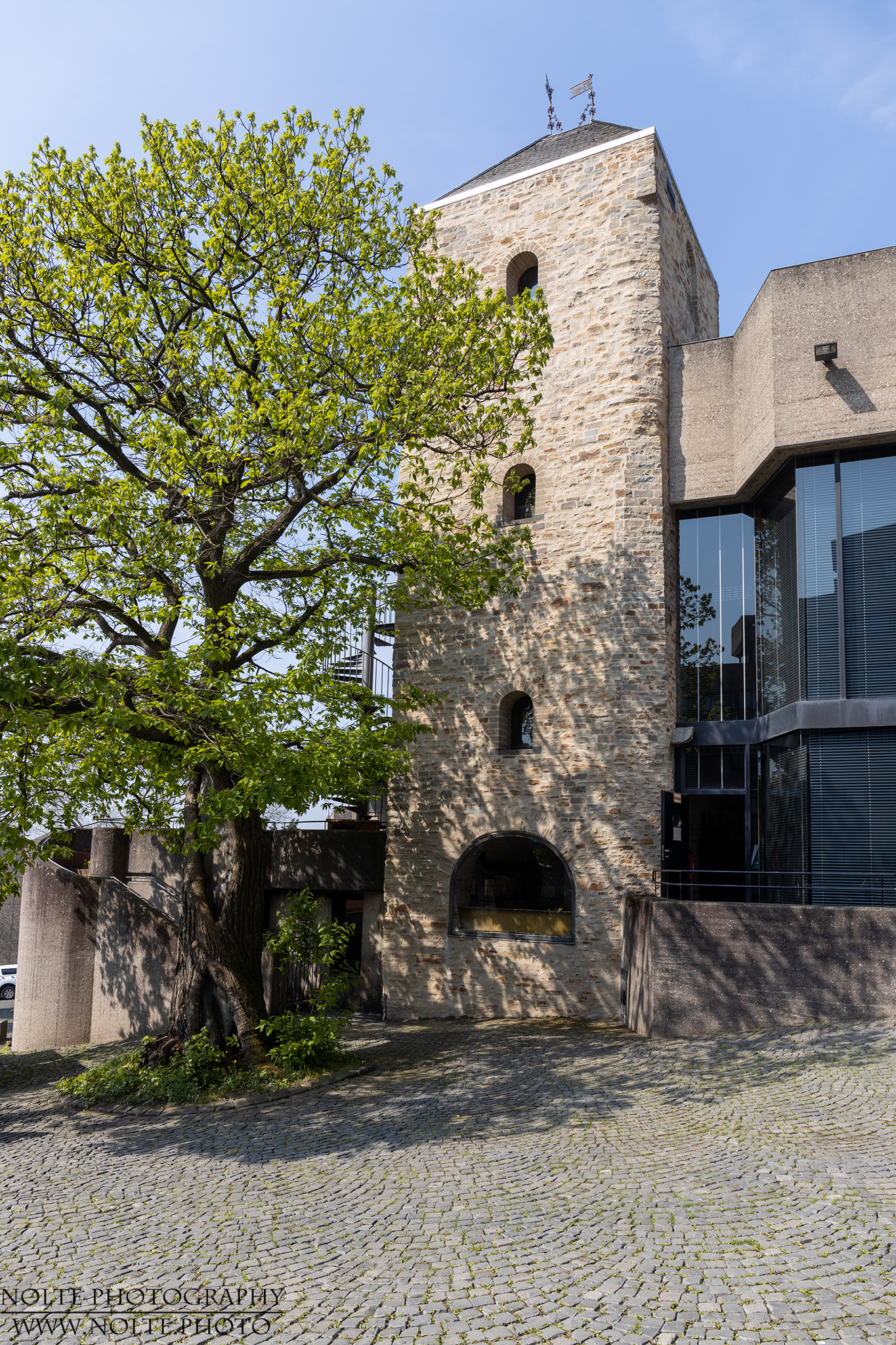 ALter Burgturm neben Rathausbeton und dem einzigen Grün des Rathauses