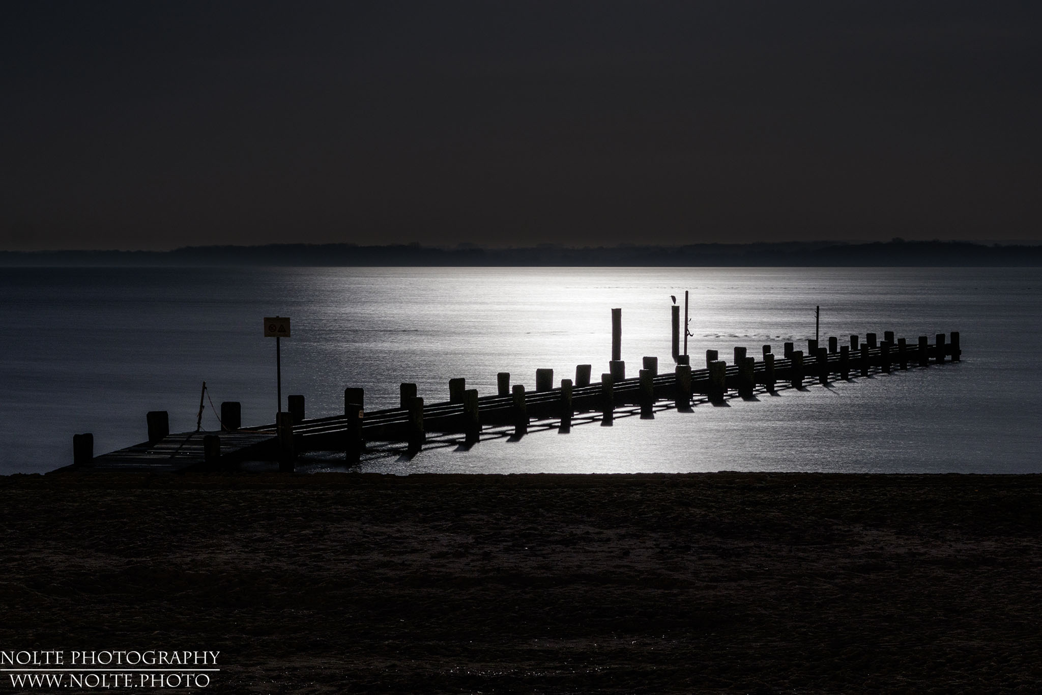 Ein kleiner Steg am Meer im hellen Licht des Vollmonds.