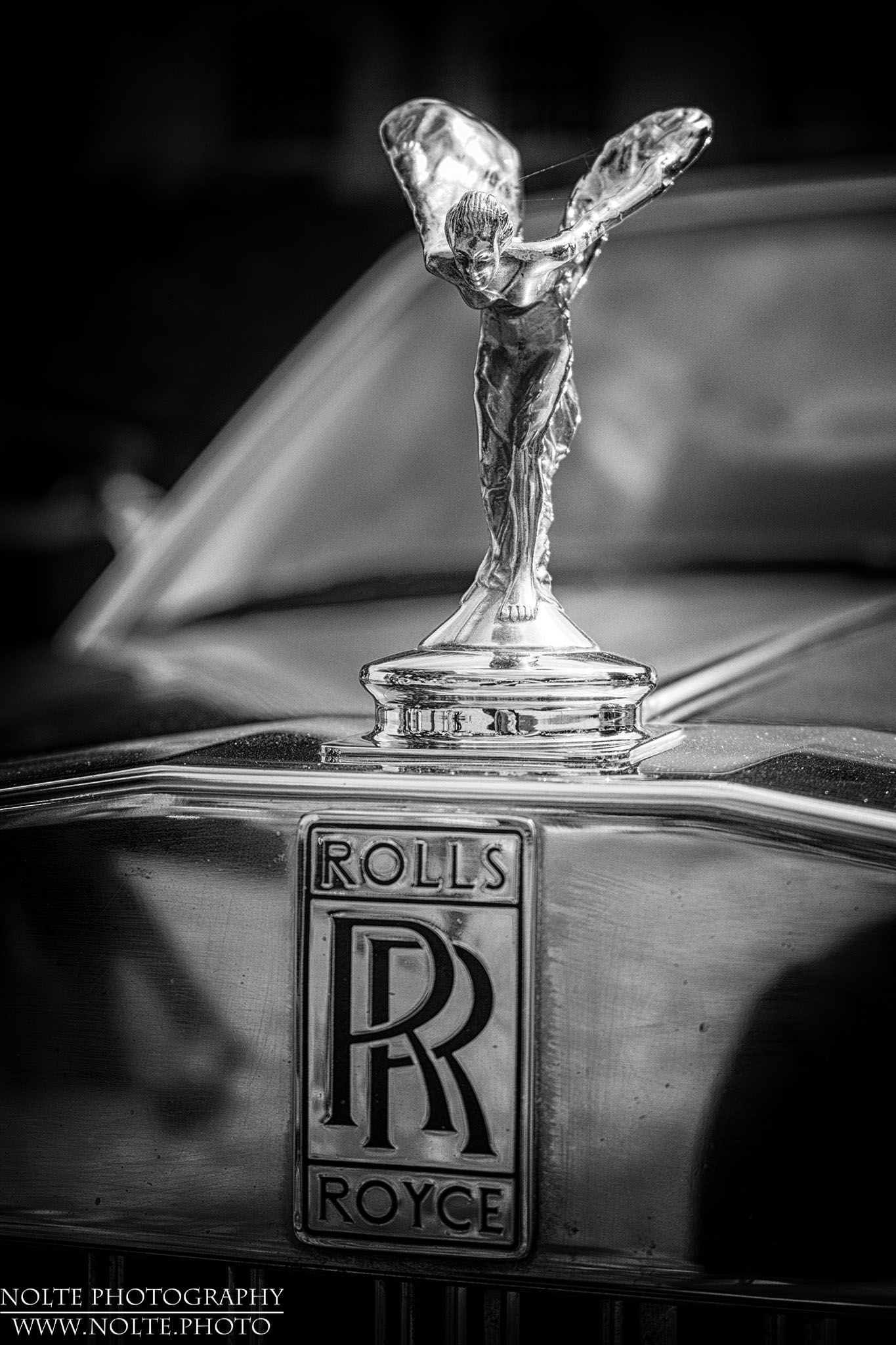 Emily verbeugt sich auf dem Kühlergrill eines Rolls Ryce Silver Spur unbekannten Baujahres.