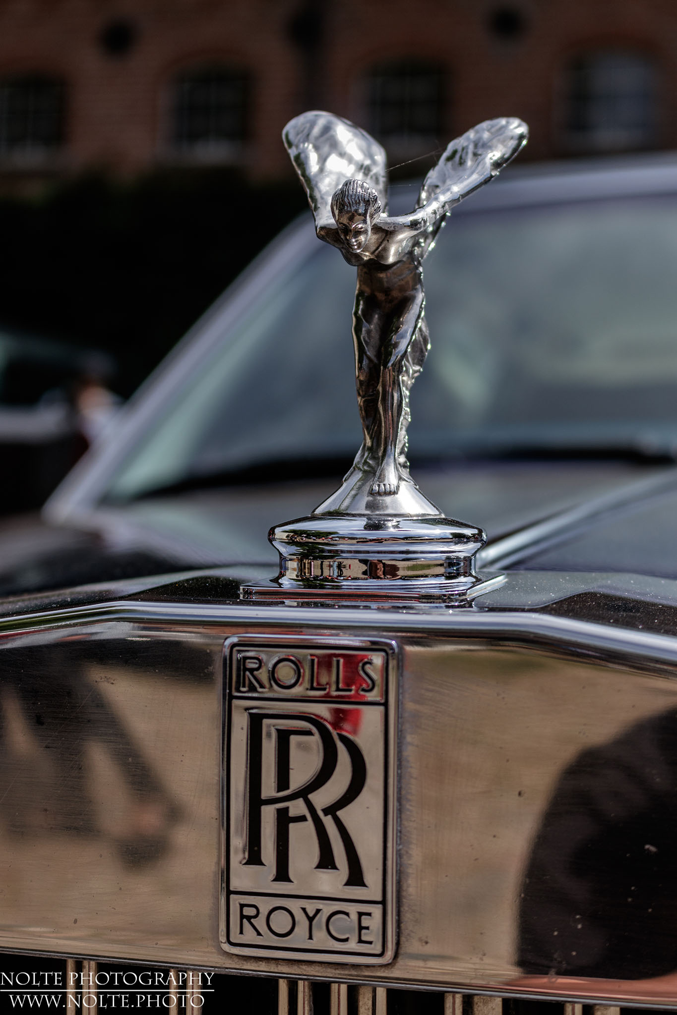 Emily verbeugt sich auf dem Kühlergrill eines Rolls Ryce Silver Spur