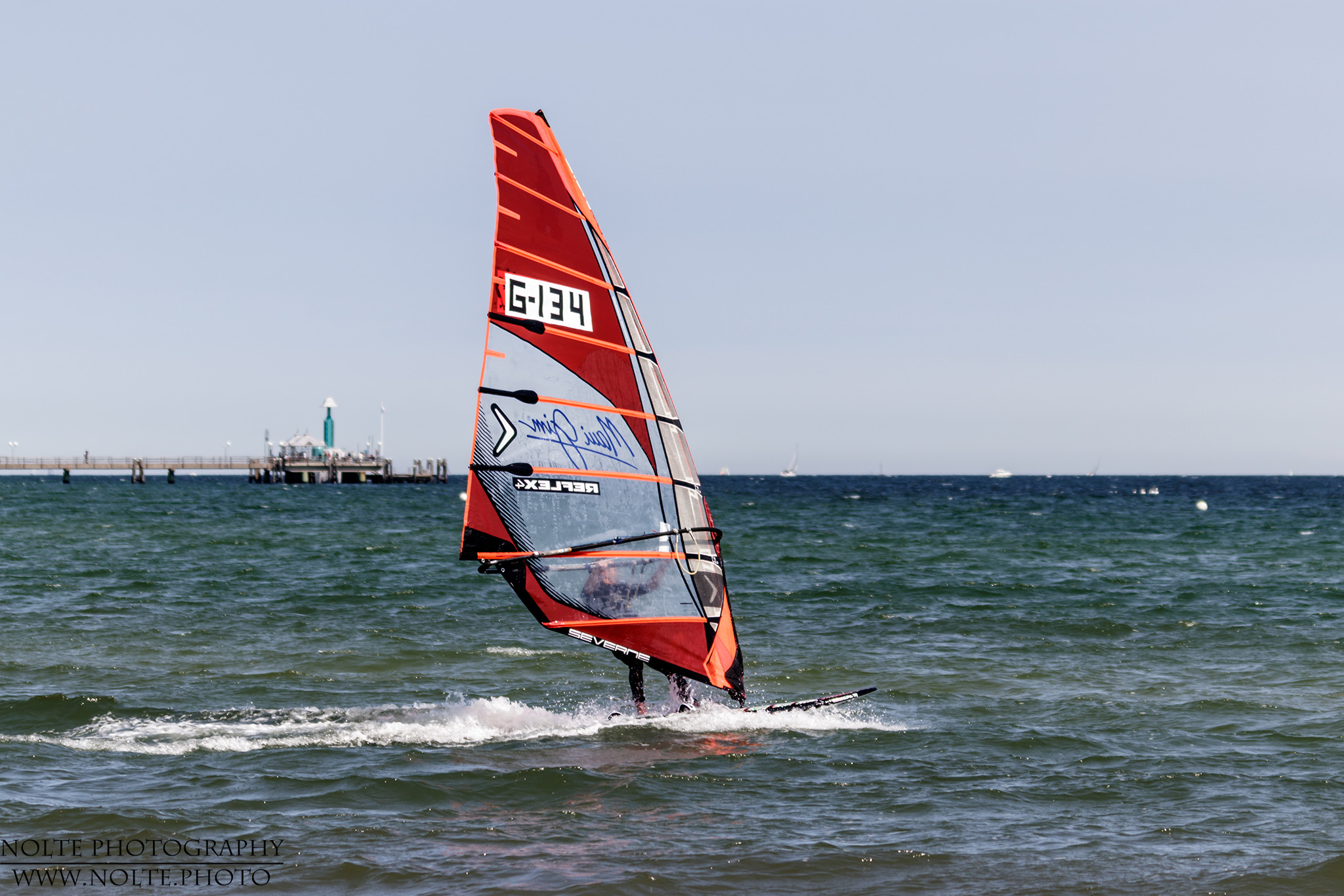 Ein Windsurfer vor der Seebrücke von Grömitz.
